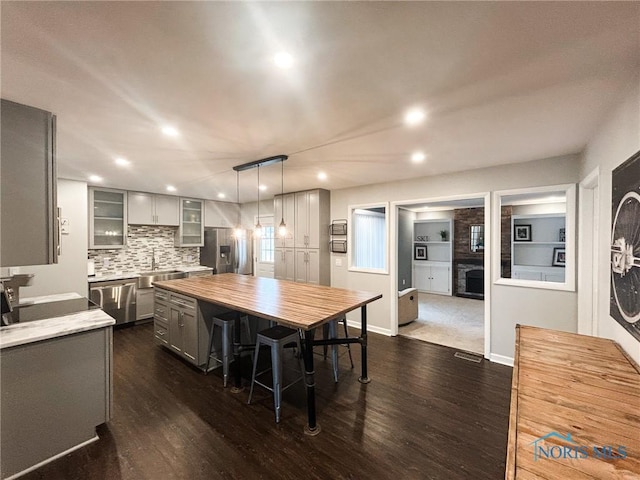 kitchen with stainless steel appliances, gray cabinets, butcher block countertops, and dark wood-style floors