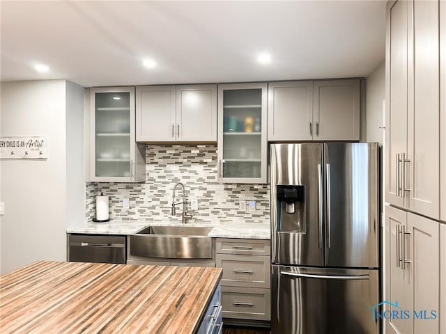 kitchen with tasteful backsplash, wood counters, stainless steel appliances, gray cabinetry, and a sink