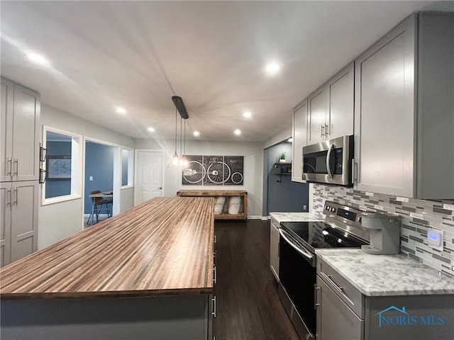 kitchen with appliances with stainless steel finishes, butcher block counters, a kitchen island, and gray cabinetry