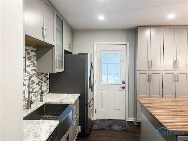 kitchen featuring dark wood finished floors, glass insert cabinets, backsplash, gray cabinets, and a sink