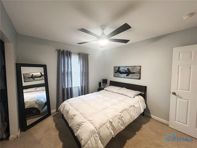 bedroom with a ceiling fan, light carpet, and baseboards