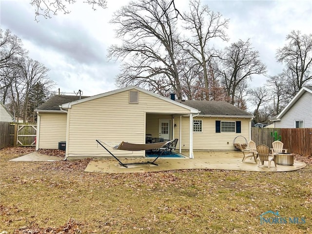 rear view of house with a fenced backyard, a patio, and a fire pit