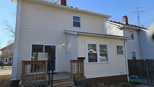 back of property featuring a chimney, a wooden deck, and fence