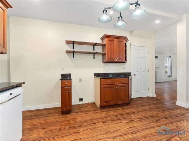 kitchen with baseboards, dark stone counters, dishwasher, and wood finished floors