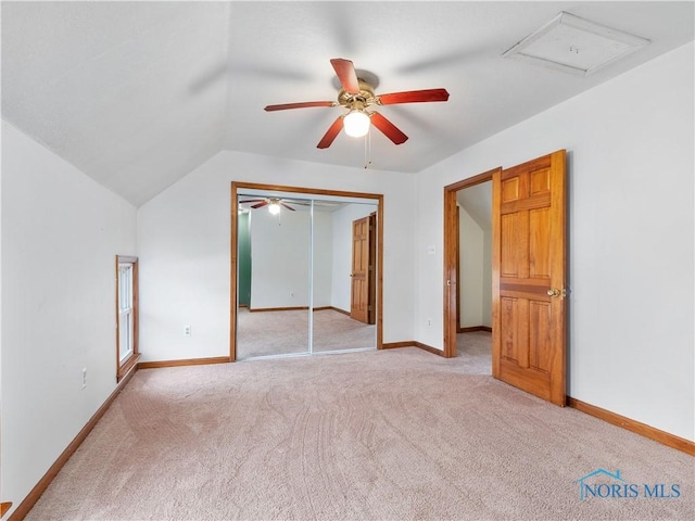 unfurnished bedroom with lofted ceiling, light carpet, a ceiling fan, baseboards, and a closet