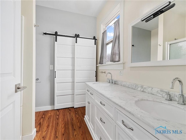 full bathroom with double vanity, baseboards, a sink, and wood finished floors