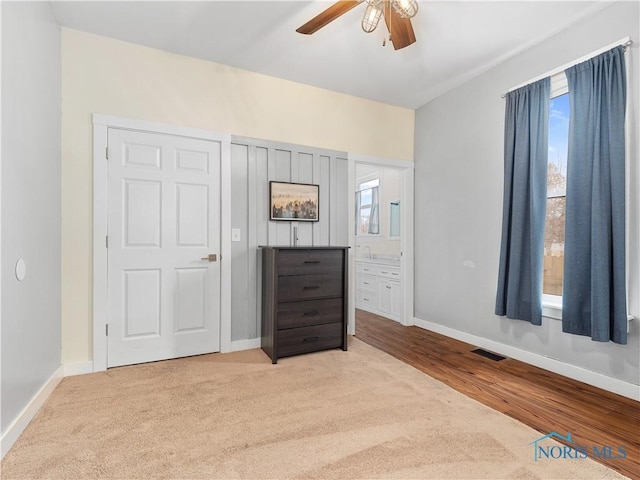 unfurnished bedroom with baseboards, a ceiling fan, and ensuite bathroom