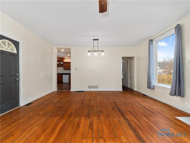 unfurnished living room featuring visible vents, baseboards, and hardwood / wood-style flooring