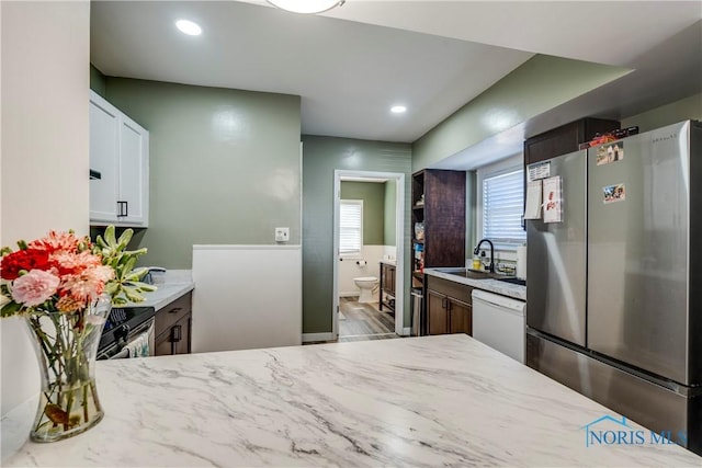 kitchen featuring stainless steel appliances, recessed lighting, white cabinets, a sink, and light stone countertops