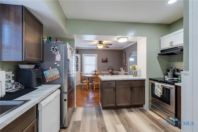 kitchen with arched walkways, white dishwasher, under cabinet range hood, light wood-style floors, and stainless steel electric range