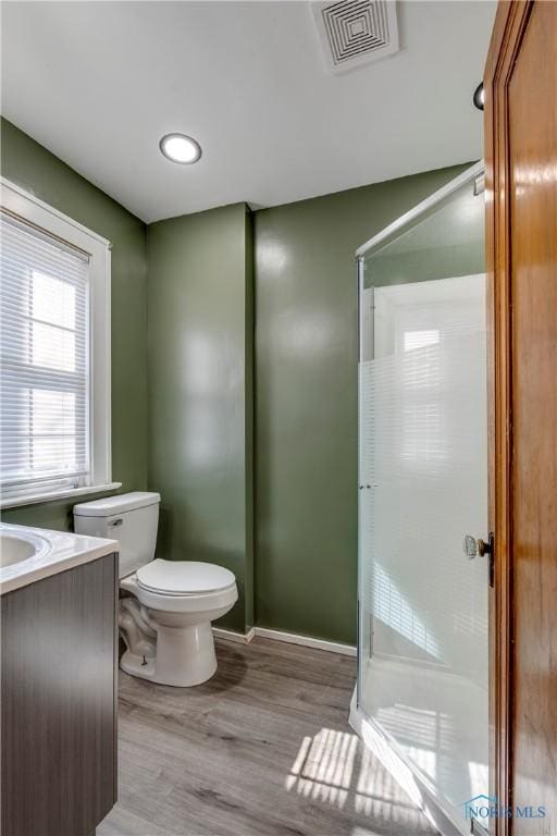 full bath featuring visible vents, toilet, vanity, a shower stall, and wood finished floors