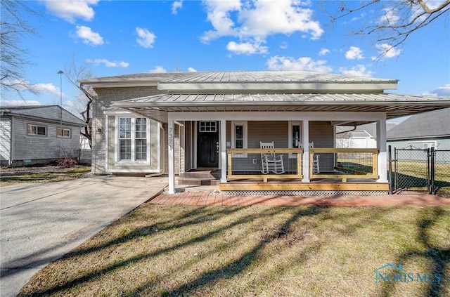 back of property with a gate, fence, a yard, covered porch, and metal roof