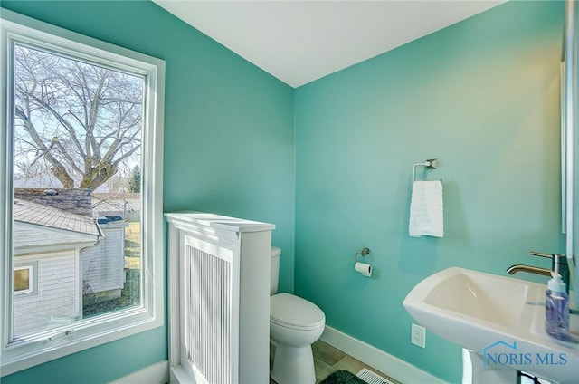 bathroom featuring a sink, baseboards, toilet, and tile patterned floors