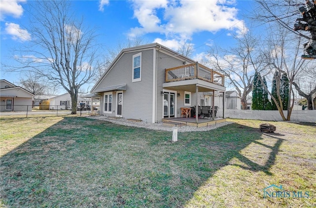 rear view of house featuring a fire pit, a lawn, a fenced backyard, and a balcony