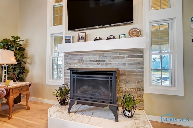 room details with a glass covered fireplace, baseboards, and wood finished floors