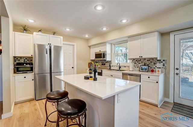 kitchen featuring a breakfast bar, light wood-style floors, white cabinetry, and appliances with stainless steel finishes