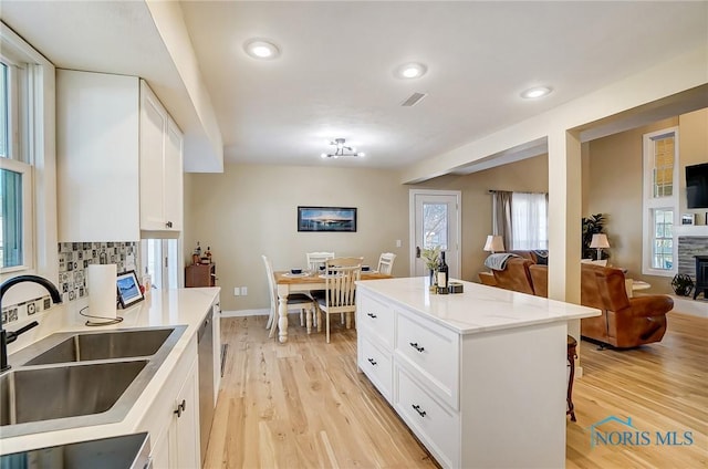 kitchen with light wood finished floors, open floor plan, tasteful backsplash, and a sink