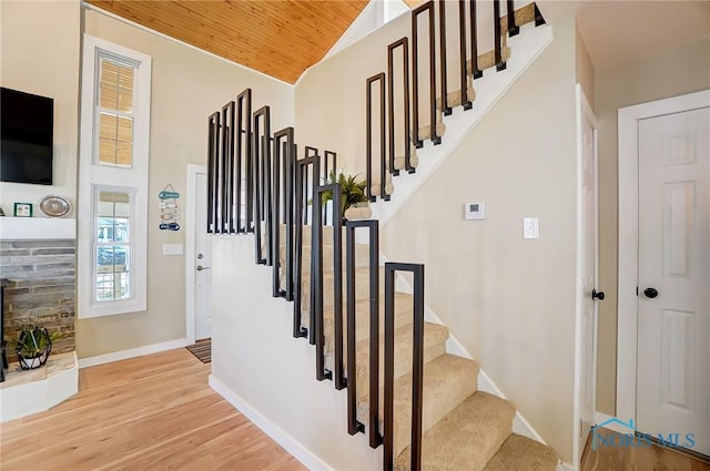 stairs with wood ceiling, wood finished floors, baseboards, and high vaulted ceiling