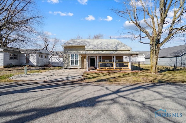 view of front facade with a porch, fence, and driveway