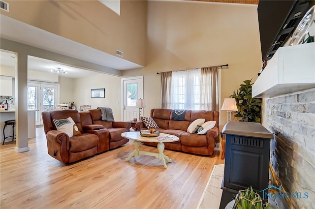 living room with light wood finished floors, visible vents, and a high ceiling