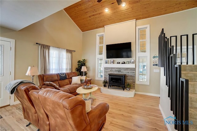 living room featuring light wood-type flooring, a fireplace with raised hearth, and wooden ceiling