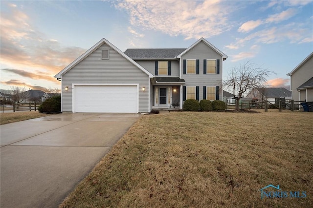 traditional-style home featuring a garage, driveway, a lawn, and fence