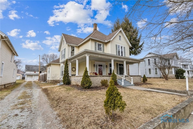 view of front facade with driveway, covered porch, an outdoor structure, and a chimney