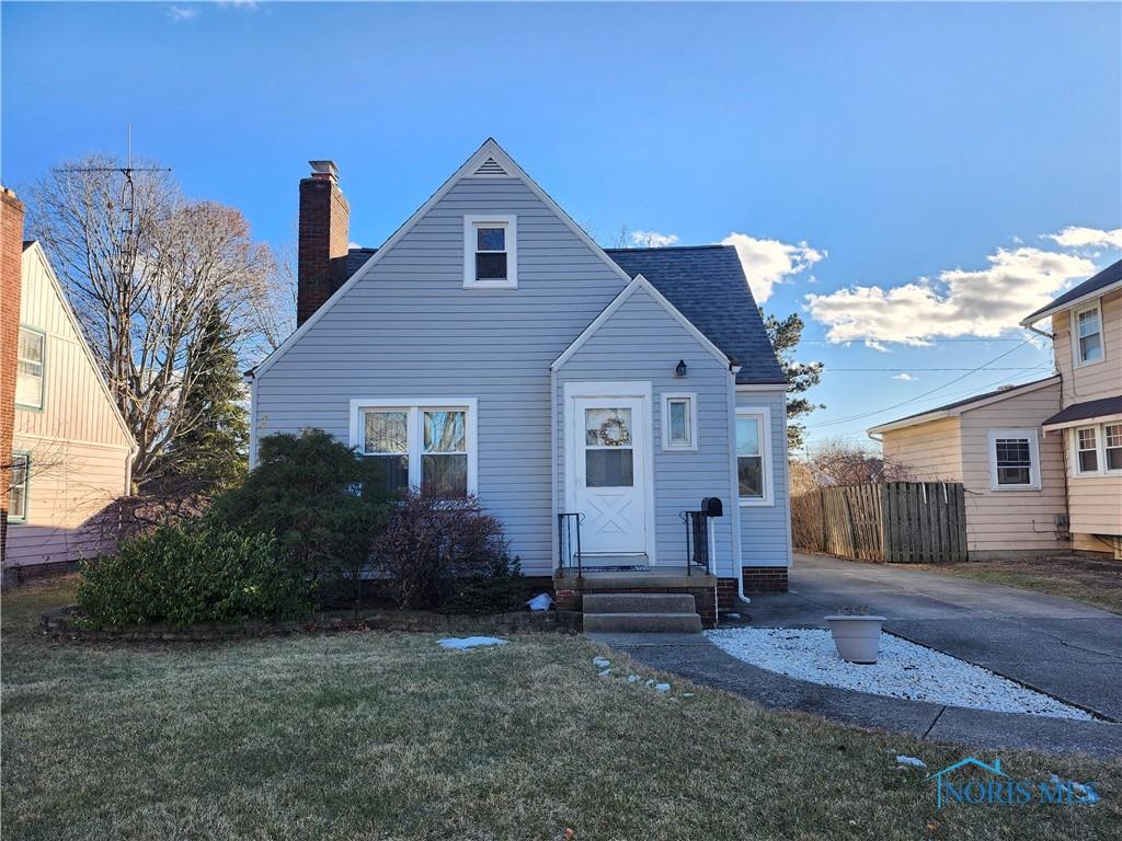 view of front of property with entry steps, a shingled roof, a chimney, and a front yard