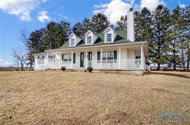 view of front of home with covered porch, a chimney, and a front yard