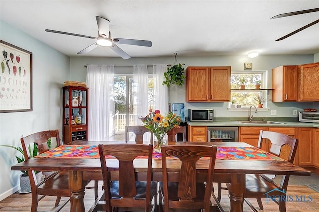 kitchen featuring a ceiling fan, brown cabinets, stainless steel microwave, and a sink