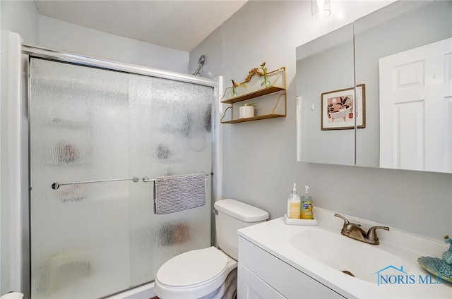 bathroom with toilet, a shower stall, and vanity