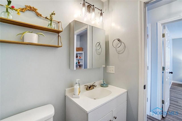 bathroom featuring wood finished floors, vanity, and toilet