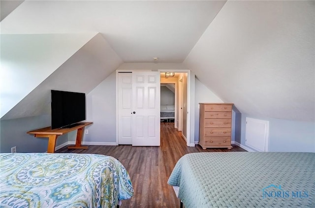 bedroom with lofted ceiling, a closet, baseboards, and wood finished floors