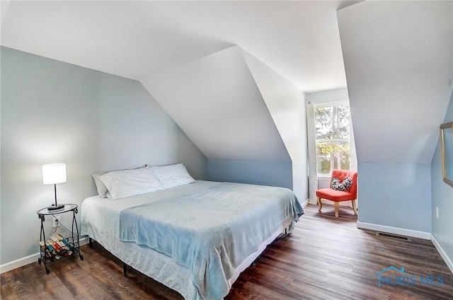 bedroom featuring visible vents, baseboards, vaulted ceiling, and wood finished floors