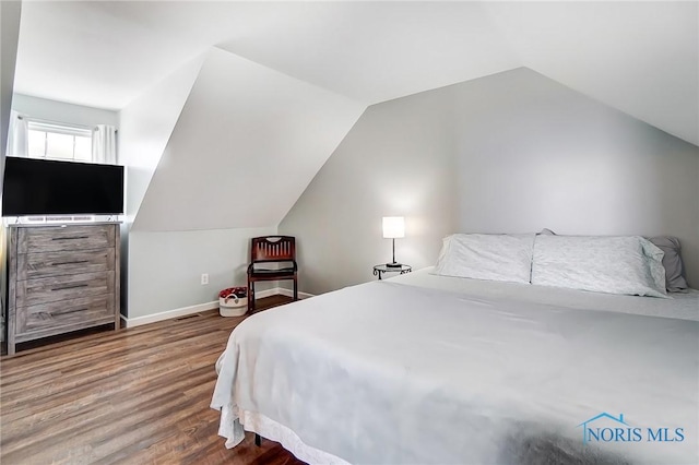 bedroom featuring vaulted ceiling, baseboards, and wood finished floors