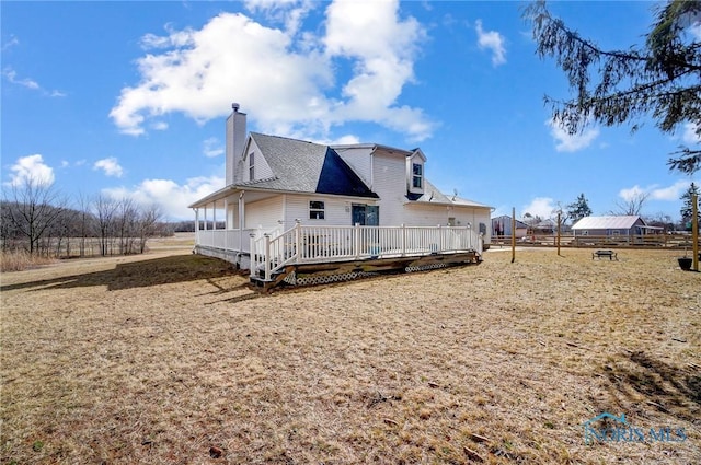 rear view of property featuring a chimney and a wooden deck