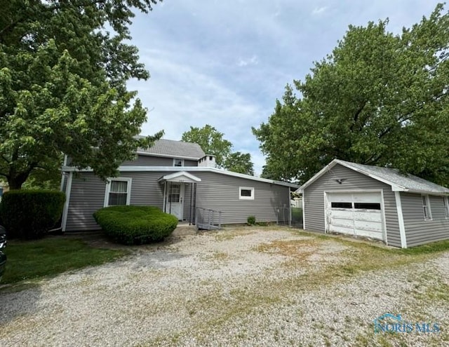 view of front facade featuring an outbuilding, driveway, and a detached garage