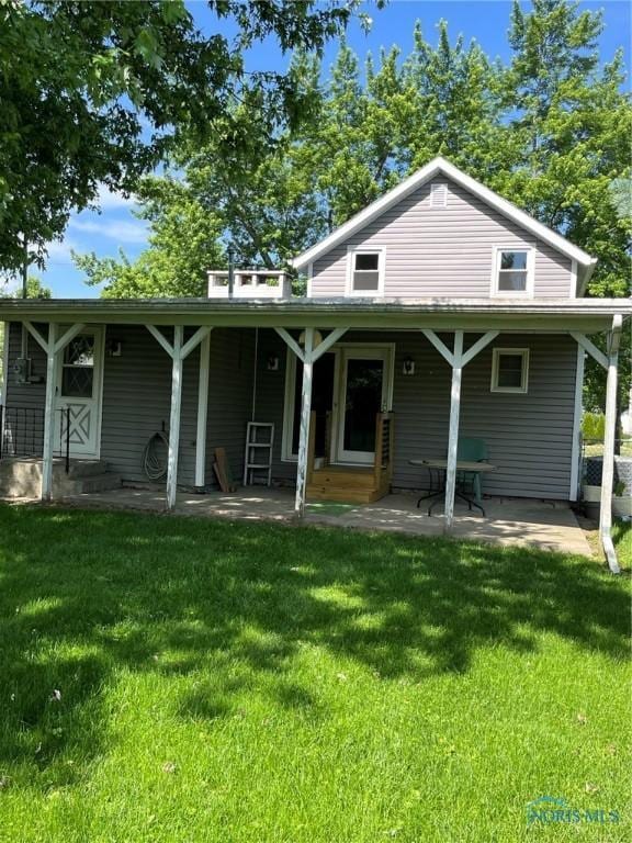 rear view of property with entry steps, a lawn, and a patio