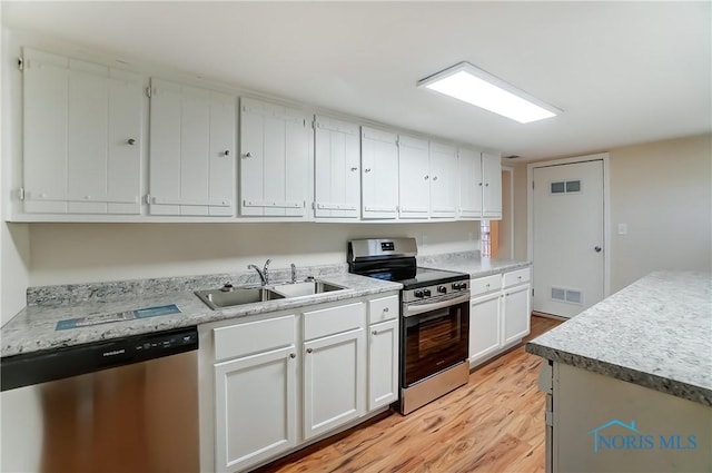 kitchen with visible vents, appliances with stainless steel finishes, light wood-style floors, white cabinetry, and a sink