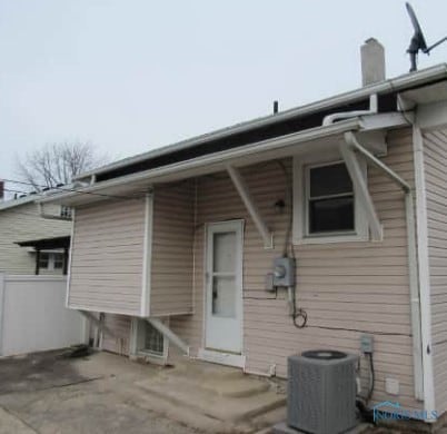 back of property featuring cooling unit, fence, and a chimney