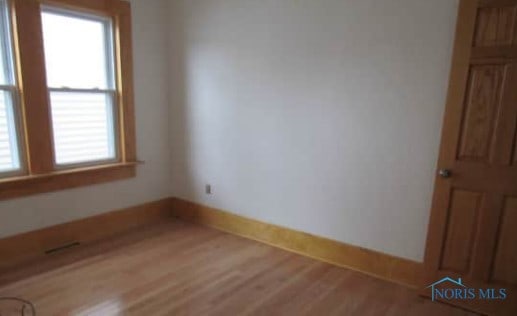 unfurnished room with a healthy amount of sunlight, baseboards, and wood finished floors