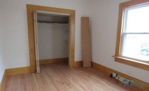 unfurnished bedroom featuring a closet, baseboards, and wood finished floors