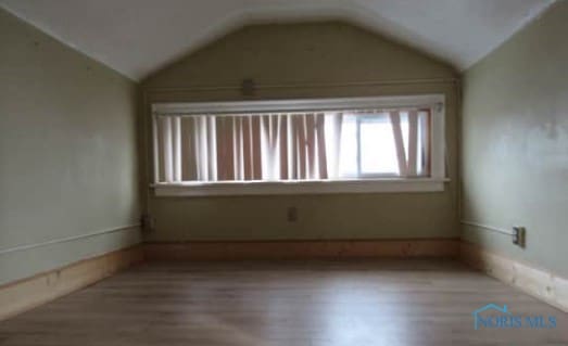 spare room featuring lofted ceiling and wood finished floors