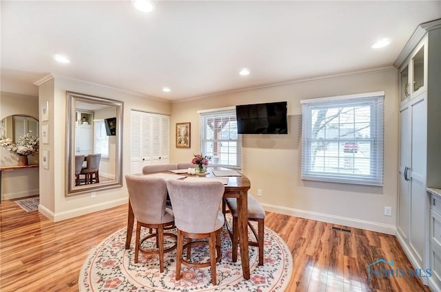 dining space featuring light wood-style floors, baseboards, crown molding, and recessed lighting