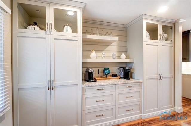 kitchen with open shelves, glass insert cabinets, white cabinets, light stone countertops, and light wood-type flooring