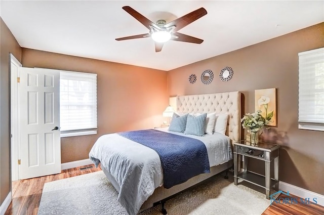 bedroom featuring visible vents, wood finished floors, a ceiling fan, and baseboards