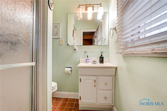 full bathroom featuring toilet, vanity, baseboards, tile patterned floors, and a shower with door