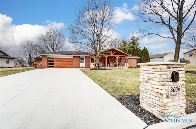 view of front of home with a porch, an attached garage, brick siding, driveway, and a front yard