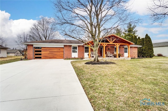 view of front of house with a front lawn, concrete driveway, brick siding, and an attached garage