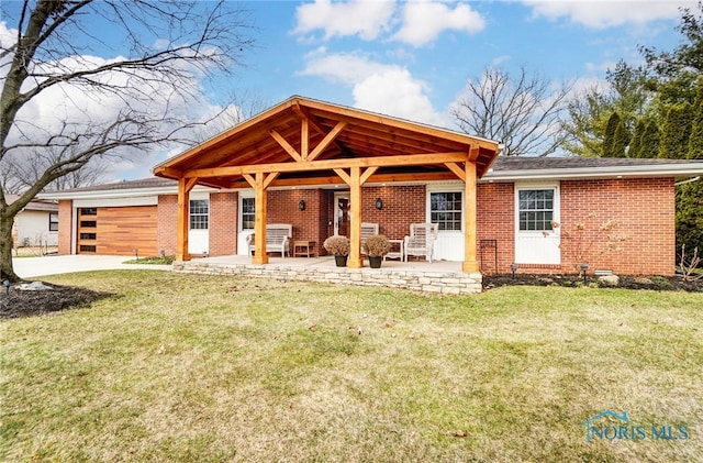 view of front of home with brick siding, concrete driveway, an attached garage, a patio area, and a front yard